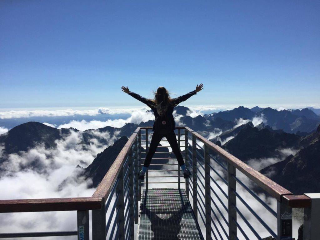 person standing on an overlook facing a mountain range